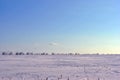 Plowed field covered with snow, line of poplar trees without leaves on the hills on horizon, winter landscape, sky Royalty Free Stock Photo