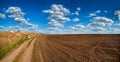 Plowed field and dirt road in spring, beautiful blue sky Royalty Free Stock Photo
