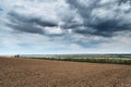 Plowed field and dramatic blue sky, soil and clouds of a bright sunny day - concept of agriculture