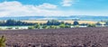 A plowed field near the river on a sunny day. Rural landscape with white clouds in the blue sky Royalty Free Stock Photo