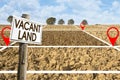 Plowed field with signboard and Vacant Land text - Land plot management - Real estate concept with a vacant land available for