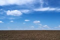 Plowed field, soil and clouds of a bright sunny day - concept of agriculture Royalty Free Stock Photo