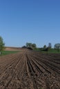 Plowed field in spring on a farm in a village on a sunny day with blue sky and trees Royalty Free Stock Photo