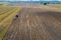 Plowing the ground with a tractor to which a plow is attached, aerial view. Autumn agricultural work.