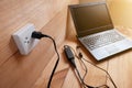 Plug in Adapter power cord charger of laptop computer On wooden floor Royalty Free Stock Photo