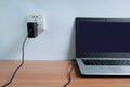 Plug in power outlet adapter cord charger on a white wall of the laptop computer on Wooden Royalty Free Stock Photo