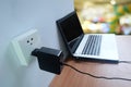 Plug in power outlet adapter cord charger on a white wall of the laptop computer on Wooden Royalty Free Stock Photo