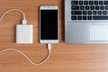 Plug in USB charger from powerbank input mobile phone or cell phone and laptop computer on wooden floor Royalty Free Stock Photo