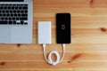 Plug in USB charger from powerbank input mobile phone or smartphone and laptop computer on wooden floor, Top view Royalty Free Stock Photo