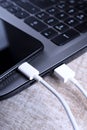 Plug in USB cord,cable charger,charging,charged and data transfer of the mobile phone,smartphone with a laptop on wooden floor, Royalty Free Stock Photo