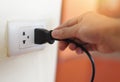 Plug in wall with hand and black power cord cable - Unplug or plugged in concept socket on electric plug on wall Royalty Free Stock Photo