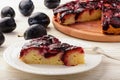 Plum biscuit cake on white wooden background.