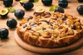 Plum biscuit cake on wooden background.