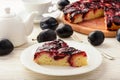 Plum bisquit cake on white wooden background.