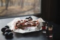 Plum cake with fresh plums on a dark background, 2 glasses with plum liqueur on a dark table by the window Royalty Free Stock Photo