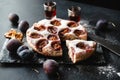 Plum cake with fresh plums on a dark background, knife,  glasses with liqueur Royalty Free Stock Photo