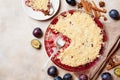 Plum crumble with aromatic spice on kitchen table top view. Autumn pastry.