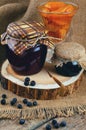 Plum jam and blueberry jam into jars, apricot jam on a background of jute. Raw blueberries