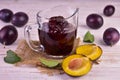 Plum jam in a glass gravy boat on a berm wooden background.