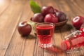 Plum liqueur in a glass and a bottle of fresh plums on a wooden table. Royalty Free Stock Photo