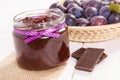 Plum marmalade or jam in glass jar, fruits in wicker basket and chocolate, sweet dessert concept Royalty Free Stock Photo