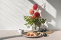 Plum pie piece on plate, cup of tea, vase with autumn flower bouquet on table, aesthetic sunlight shadows on white wall Royalty Free Stock Photo