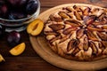 Plum pie on a rustic wood background with plums