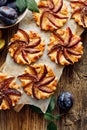 Plum tarts, fruit pastries with cinnamon on awooden background, delicious dessert with puff pastry and fruits
