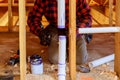 Plumber applying glue to PVC pipe under construction in new home