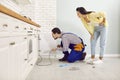 Plumber uses a drain cable to clean a clogged pipe in a young woman& x27;s kitchen sink Royalty Free Stock Photo