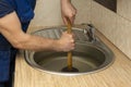 A plumber clear a blockage in a kitchen sink with a plunger Royalty Free Stock Photo