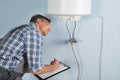 Plumber with clipboard looking at electric boiler