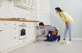 Plumber cleaning clogged pipes under the kitchen sink with the help of a drain cable Royalty Free Stock Photo