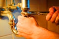 Plumber fixing bath faucet with an adjustable wrench Royalty Free Stock Photo
