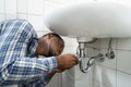 Plumber Fixing Pipe In Bathroom. Plumbing Maintenance Royalty Free Stock Photo