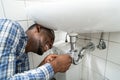 Plumber Fixing Pipe In Bathroom. Plumbing Maintenance Royalty Free Stock Photo