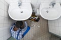 Plumber Fixing Pipe In Bathroom. Plumbing Maintenance Royalty Free Stock Photo