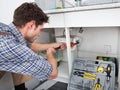 Plumber fixing sink in kitchen Royalty Free Stock Photo