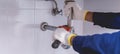 Plumber fixing white sink pipe with adjustable wrench