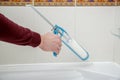 Plumber hand applying silicone sealant in the bathroom.