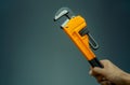 Plumber hand holding handle of chrome pipe wrench isolated on dark background. Metal monkey wrench for plumber. Mechanic tools. Royalty Free Stock Photo