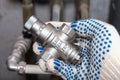 A plumber holding a new water flow regulator, pressure reducer valve in front of water pipe lines in order to replace or