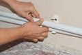 A plumber is installing central heating by laying new white polypropylene pipes into plastic waterline half clamps Royalty Free Stock Photo