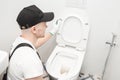 Plumber installing toilet bowl in restroom, work in bathroom