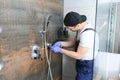 Plumber installing water taps shower stall, work in bathroom. Royalty Free Stock Photo