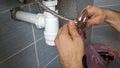 A plumber installs an end plug to a water hose. The plumber's hands attach the blanking plug to the metal braided