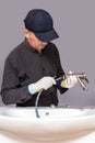 A plumber installs a faucet in a bathroom, connects a hose to the faucet