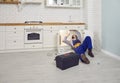 Plumber lying down on the floor under the kitchen sink and cleaning out the clogged drain Royalty Free Stock Photo