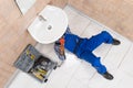 Plumber Lying On Floor Repairing Sink In Bathroom Royalty Free Stock Photo