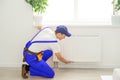 Plumber man is blocking repairs radiators of heating battery in apartment tap